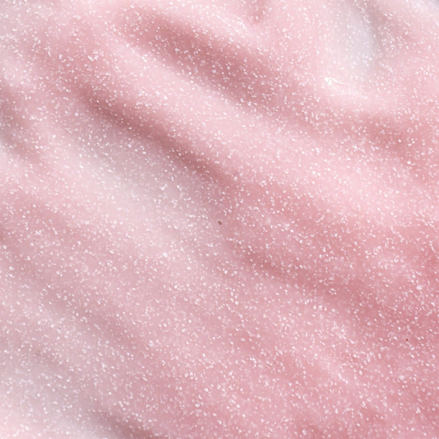Close-up of pink skincare mask with visible white cellulose beads..