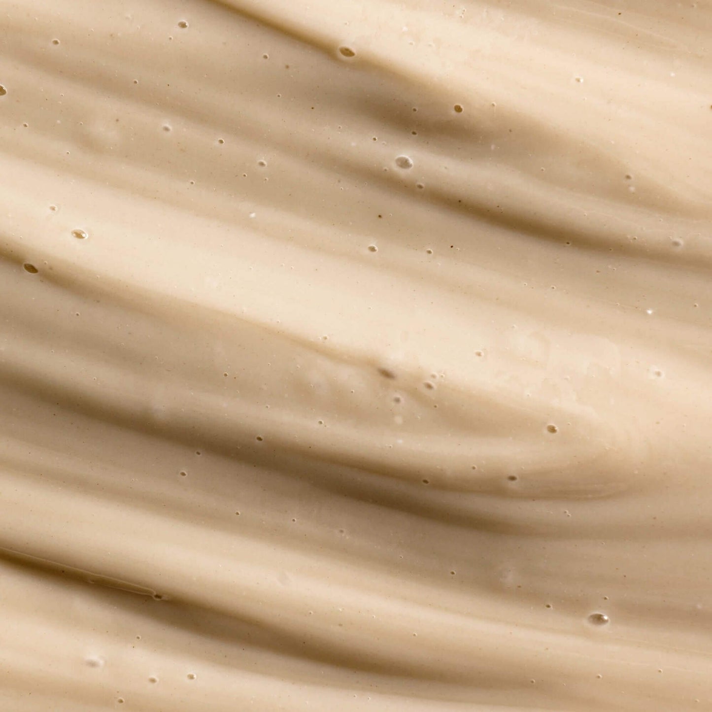 Close-up of a smooth, beige velvety skincare cream with visible texture and small air bubbles.