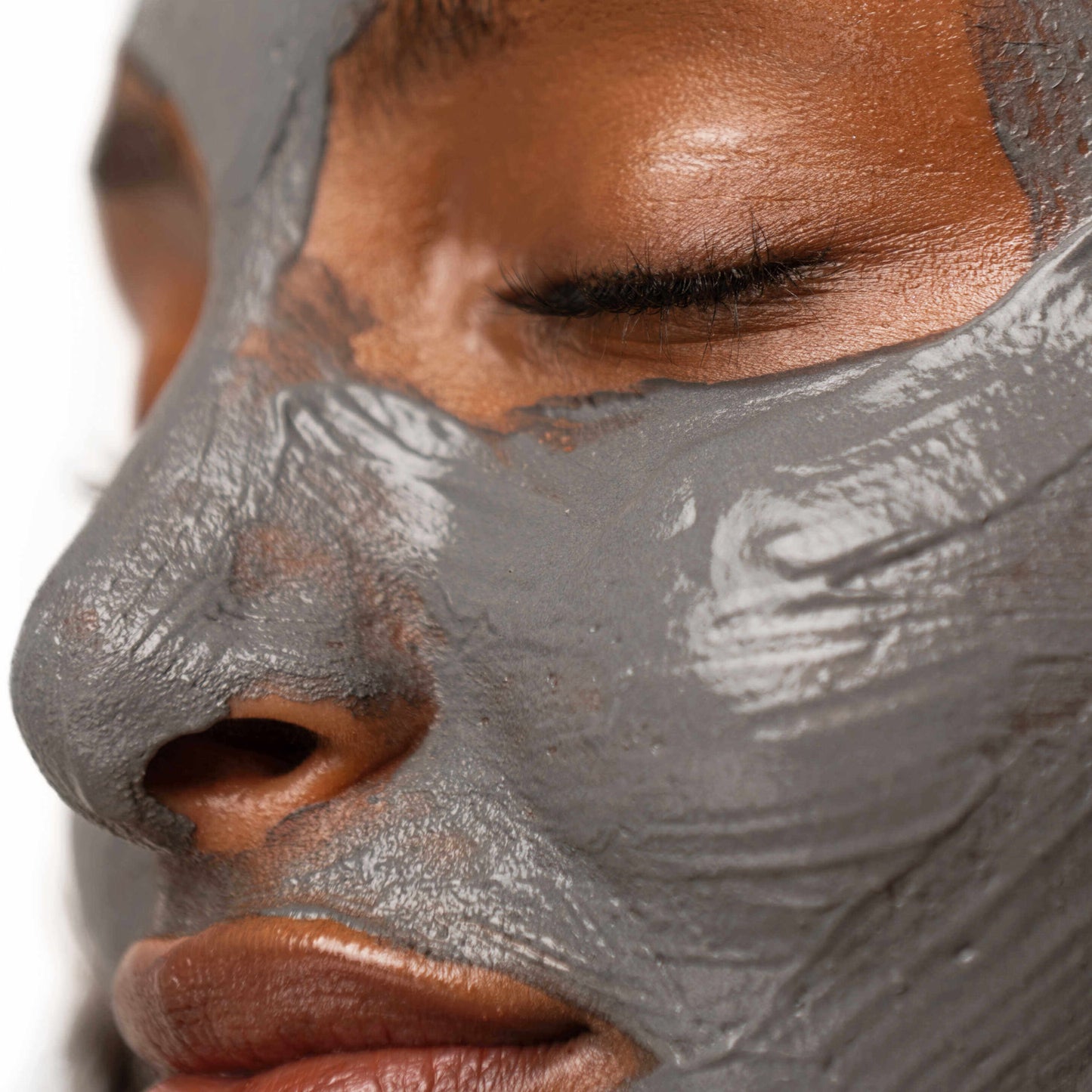 Close up of young Black woman with her face covered in grey mask and her eyes closed.